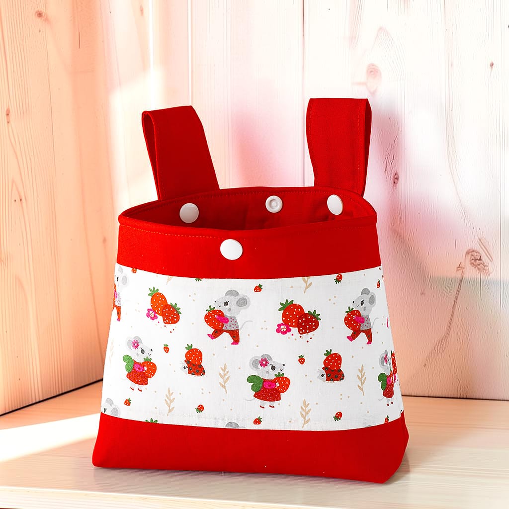 Große Lenkertasche mit Erdbeermaus-Stoff, rotem Rand und weißen Druckknöpfen.