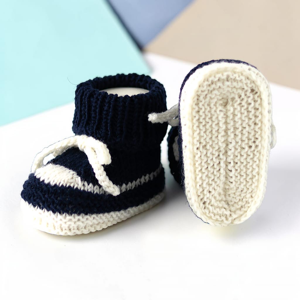 Handgestrickte Babybooties mit heller Sohle und dunkelblauem Oberteil, weiche Babyschuhe aus Wollgarn