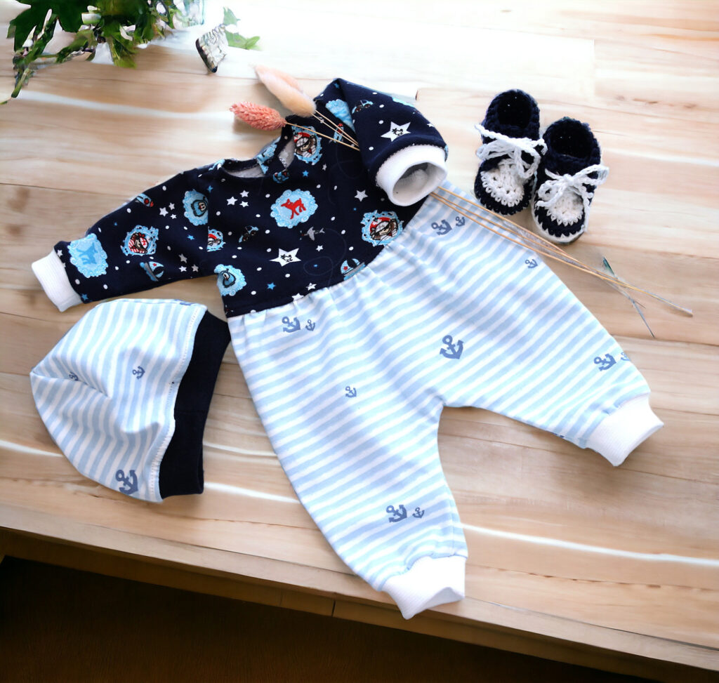 Puppenkleidungs-Set Piraten für Babypuppe 43 cm mit gestreifter Hose, Mütze und gehäkelten Turnschuhen auf Holzhintergrund