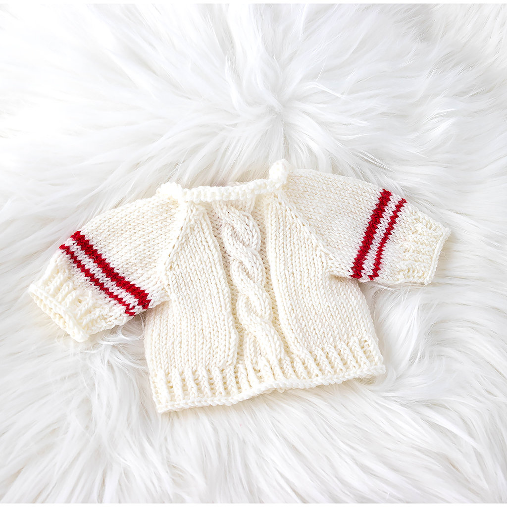 Zopfmuster eines handgestrickten Puppenpullovers aus Merinowolle