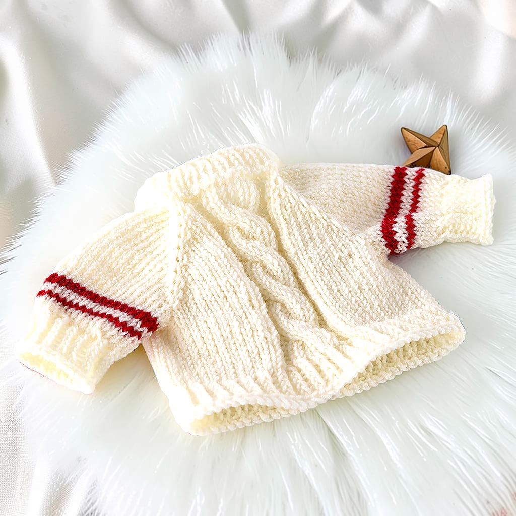 Handgestrickter naturfarbener Puppenpullover aus Merinowolle für 38 cm Waldorfpuppen. In der Mitte läuft ein Zopfmuster, die Ärmel haben zwei rote Ringelstreifen
