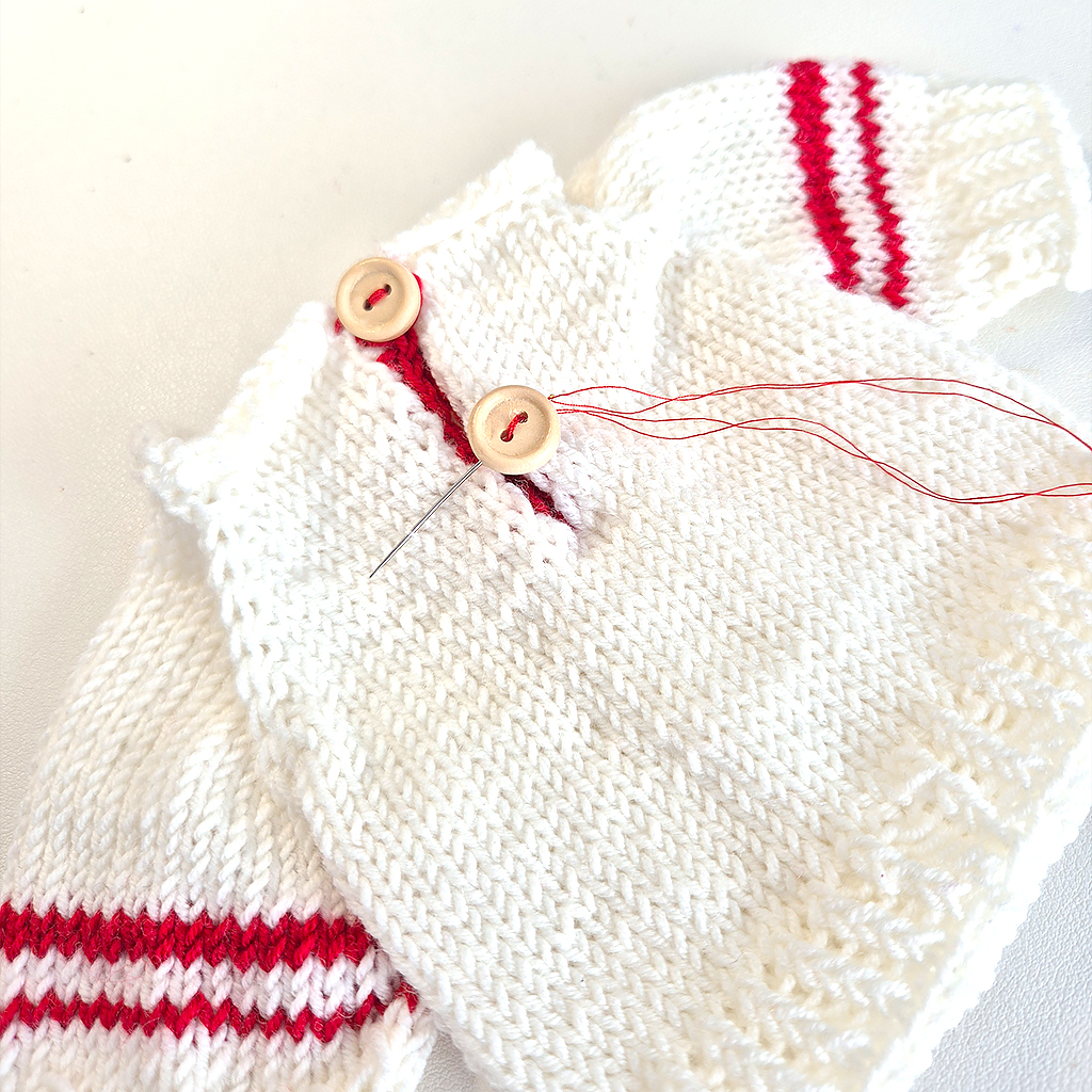 Handarbeit beim Fertigstellen eines Puppenpullovers aus Merinowolle