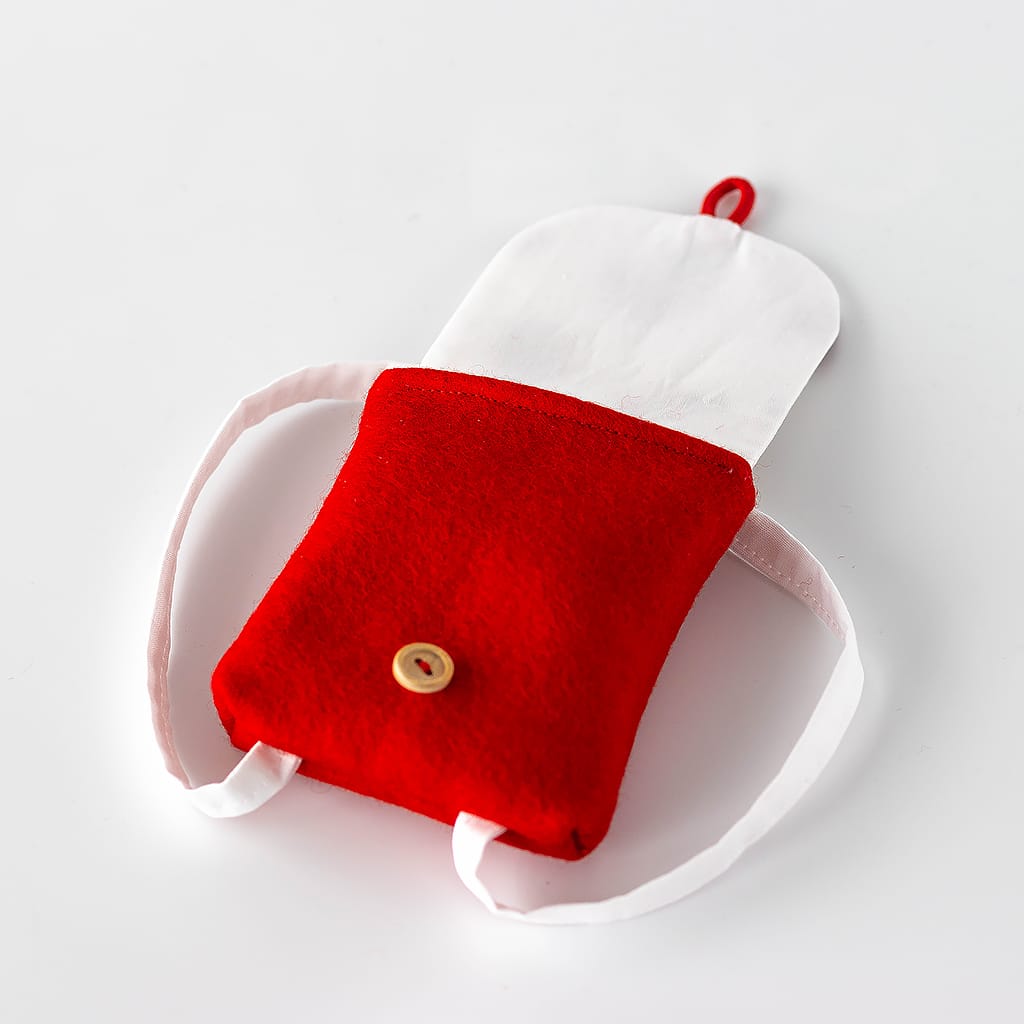 Geöffneter Puppenrucksack aus Wollfilz mit geräumigem Innenfach und Klappe mit Marienkäfer-Motiv – passendes Puppenzubehör für Waldorfpuppen.