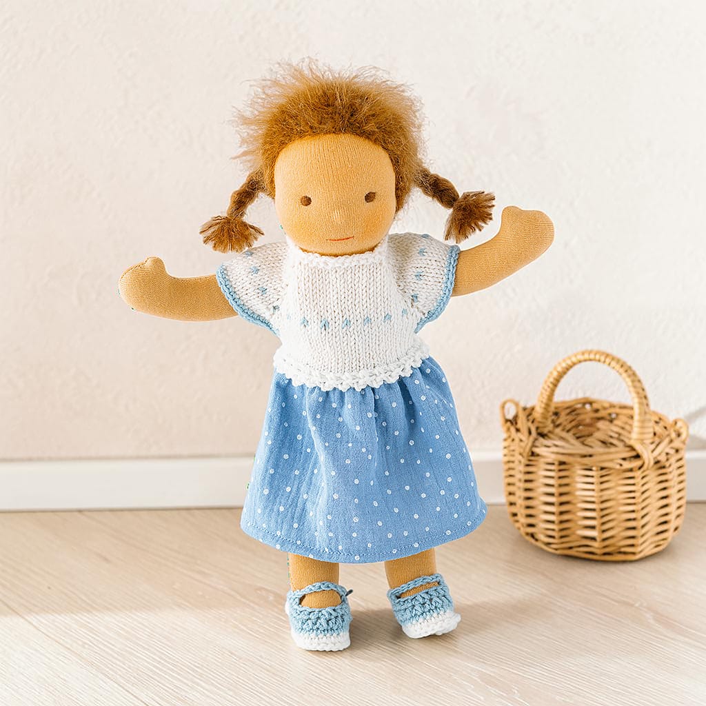 Stoffpuppe mit 32 cm Körpergröße trägt ein handgefertigtes Kleid aus weißer Merinowolle und blauem Musselin sowie passende gehäkelte Schuhe