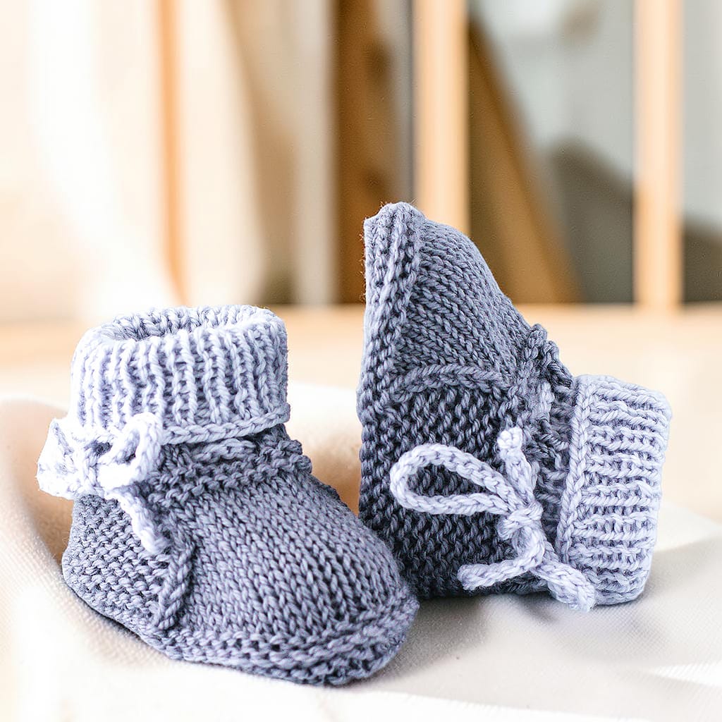 Gestrickte Babyschuhe und passende Fäustlinge in zartem Grau aus 80 Prozent Merinowolle und 20 Prozent Kaschmir