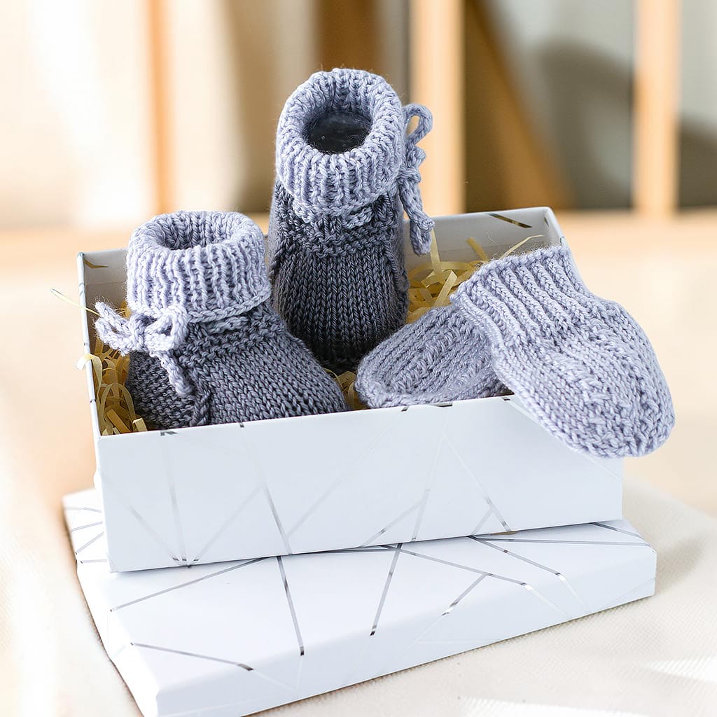 Babyset mit gestrickten Babyschuhen und Fäustlingen aus Merinowolle und Kaschmir in einer Geschenkbox